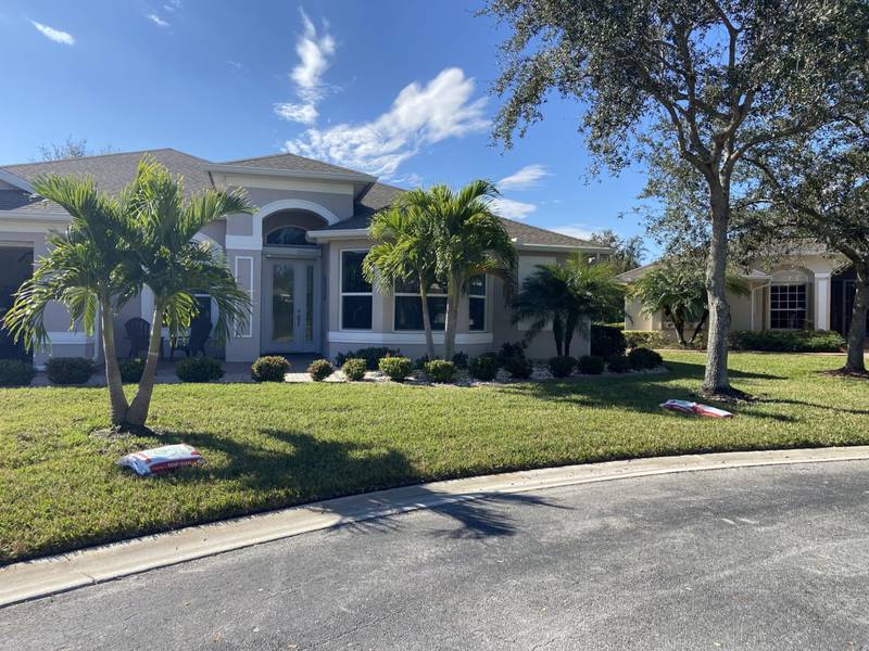 Palms and shrub beds across a front lawn at the end of a street