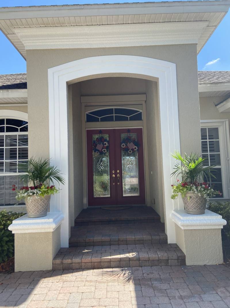 Front entry with a paver landing and potted palms on each side of the steps