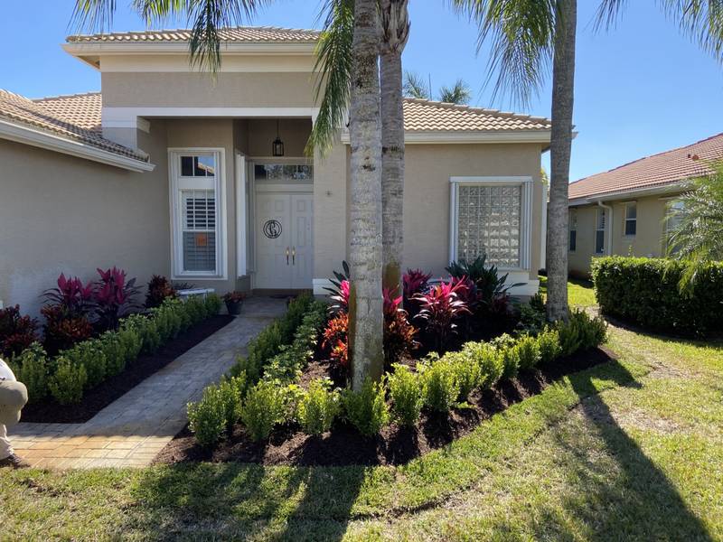 Front walk lined with clipped shrubs, bromeliads and crotons under palms