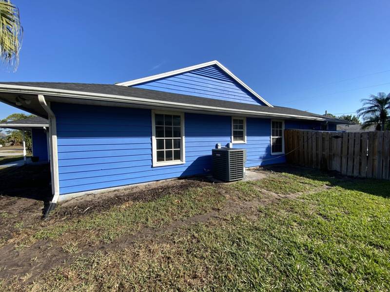 Before: bare dirt and thin grass along the side of a blue house