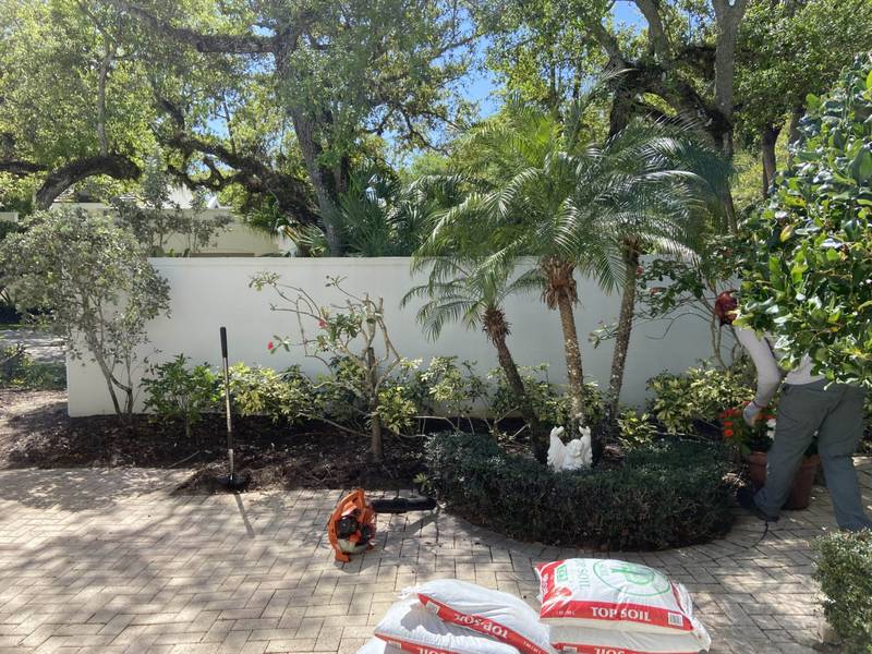 Before: a patio bed being cleared, with bags of soil on the pavers