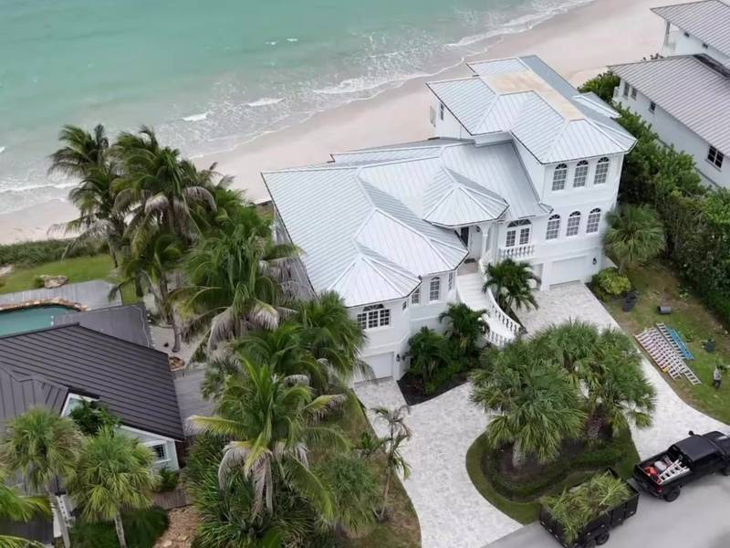 Aerial view of a beachside home with palms and the Voldscapes truck in the driveway