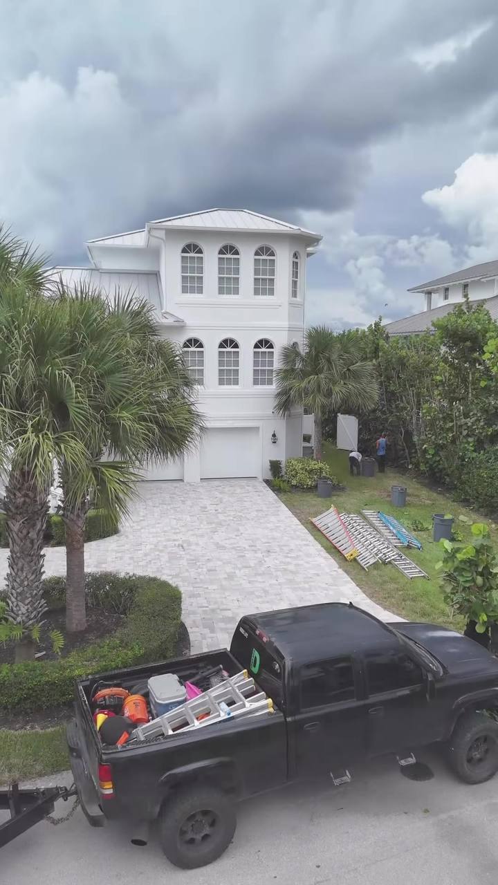 Drone shot rising over the Voldscapes truck and ladders at a large white beachside home