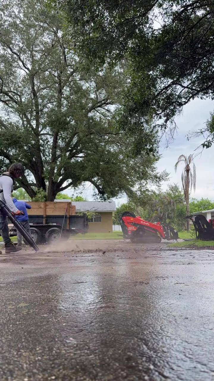 Ben and the crew cleaning up a tree job in the rain, with the track loader and trailer