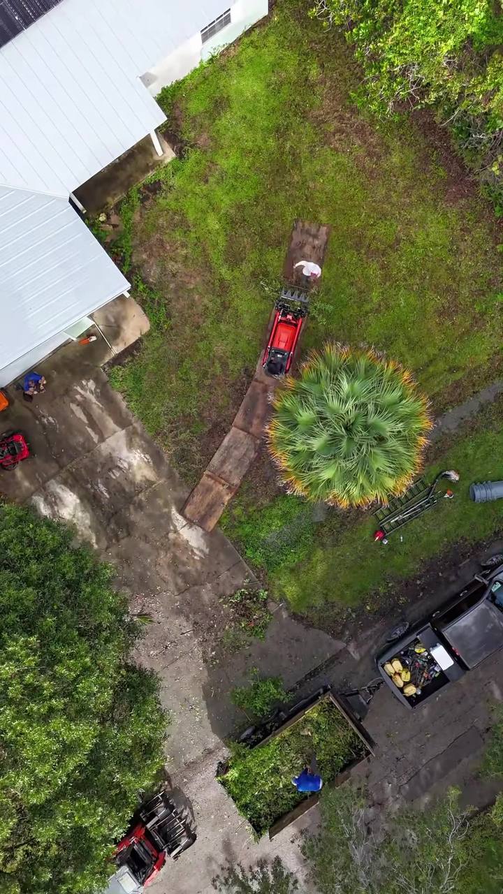Top-down drone shot of the crew working in a backyard with a track loader and trailer